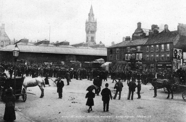 The Northern Echo: Darlington Market Place on Easter Monday. Outside the Bulls Head Hotel on Bakehouse Hill are shuggyboat swings, and makeshift tents so it looks as if a circus or menagerie has arrived to entertain the Bank Holiday crowds. There's an empty window on